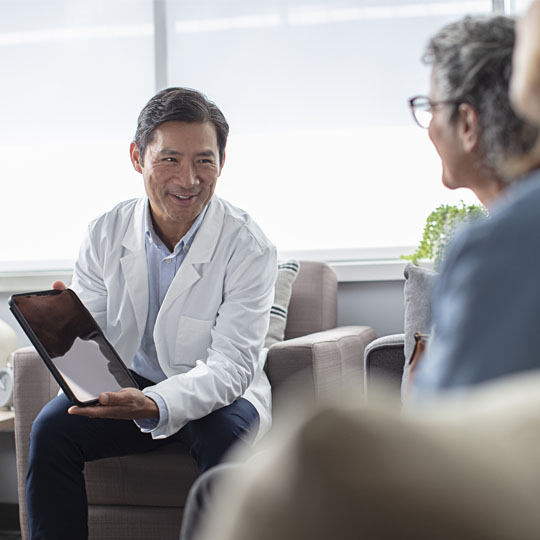 A hearing professional showing patients information on a tablet computer